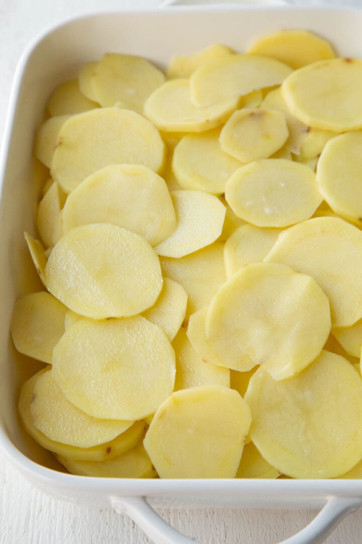 raw potato slices in a casserole dish.
