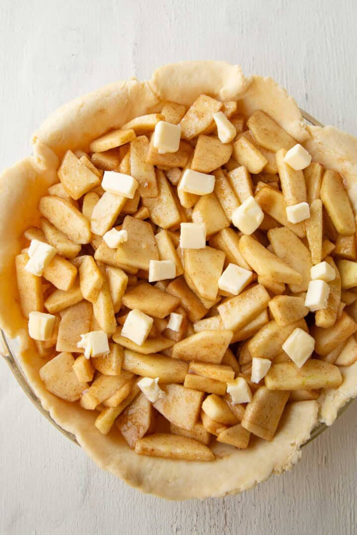 apple slices and tiny pieces of butter in an unbaked pie crust.