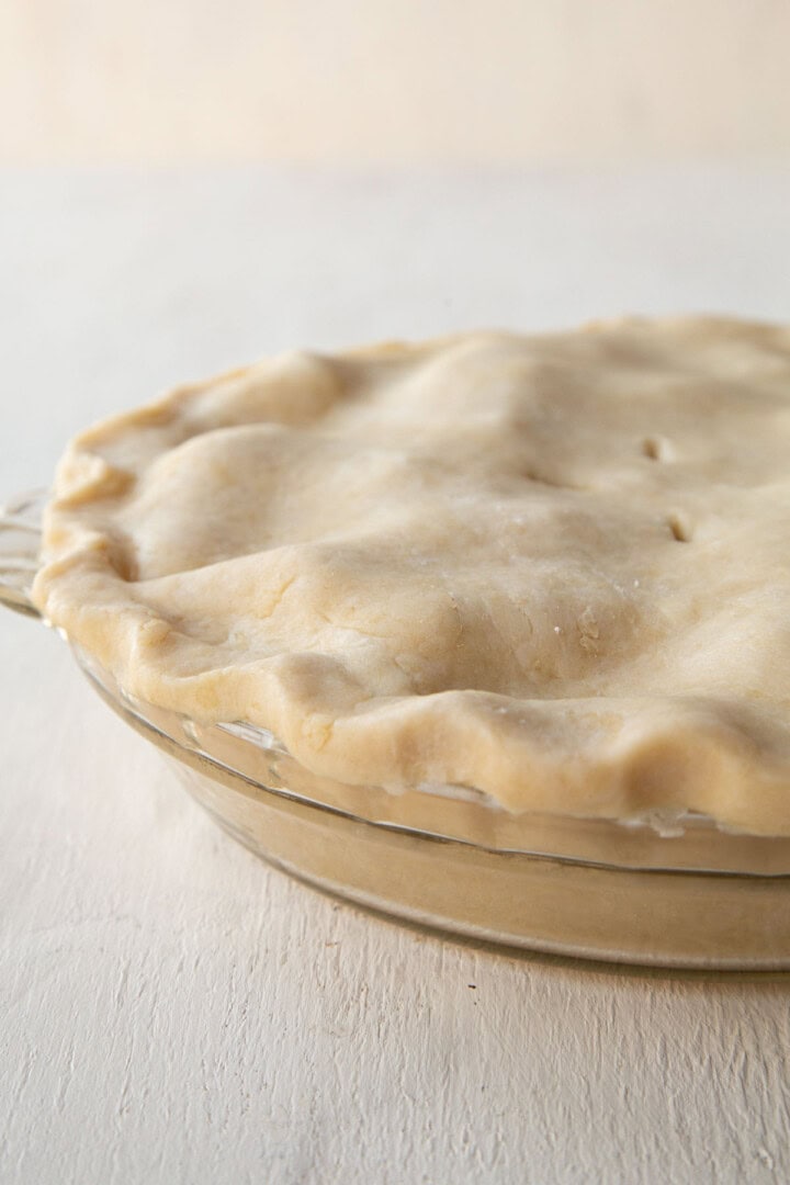 unbaked pie with an unbaked crust on top with fluted edges.