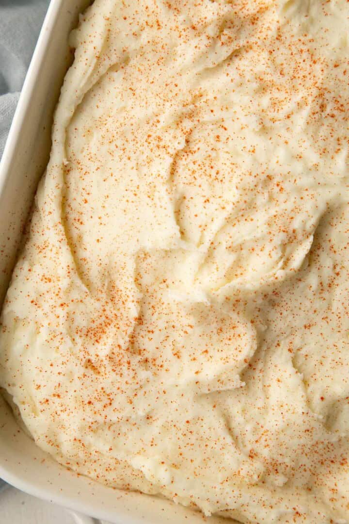 mashed potatoes in a casserole dish, topped with paprika.