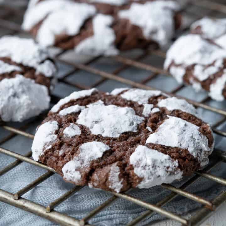 chocolate cookie with powdered sugar on the outside, on a wire rack.