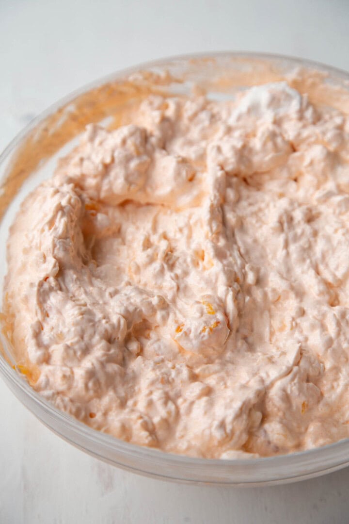 fluffy cottage cheese and orange gelatin mixture with whipped topping in a bowl.