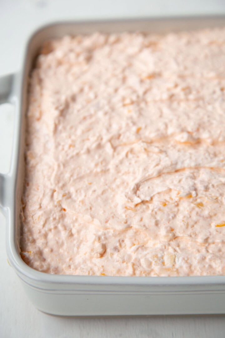 orange gelatin salad with bits of mandarin oranges in a square dish.