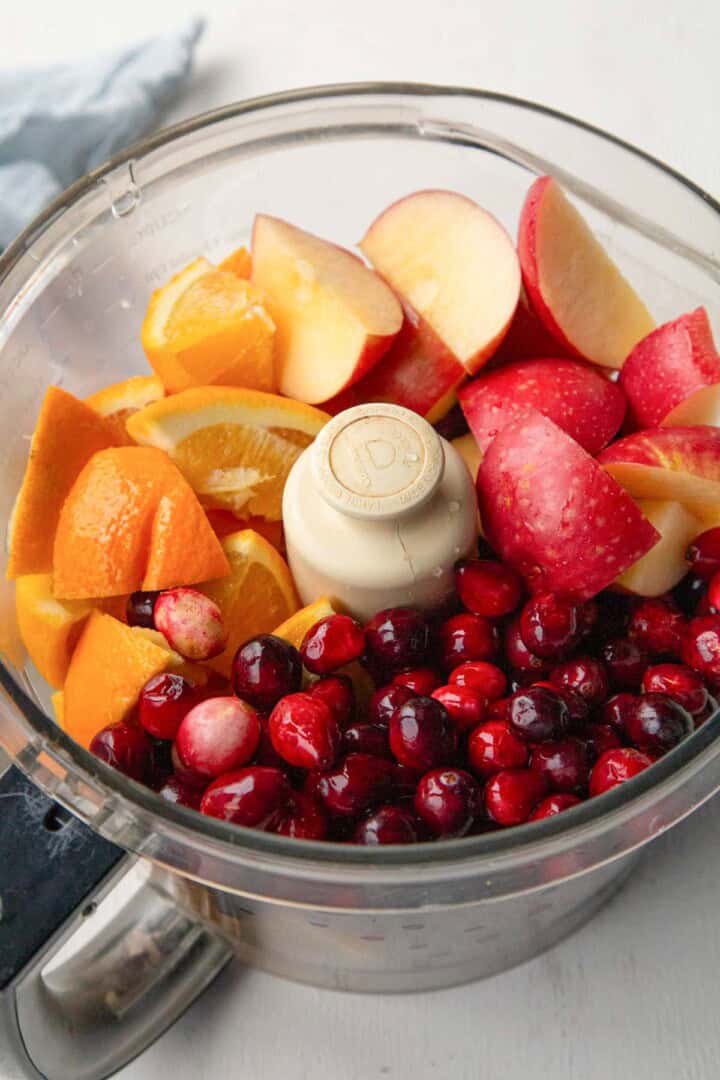 cranberries, orange chunks, and apple chunks in a food processor.