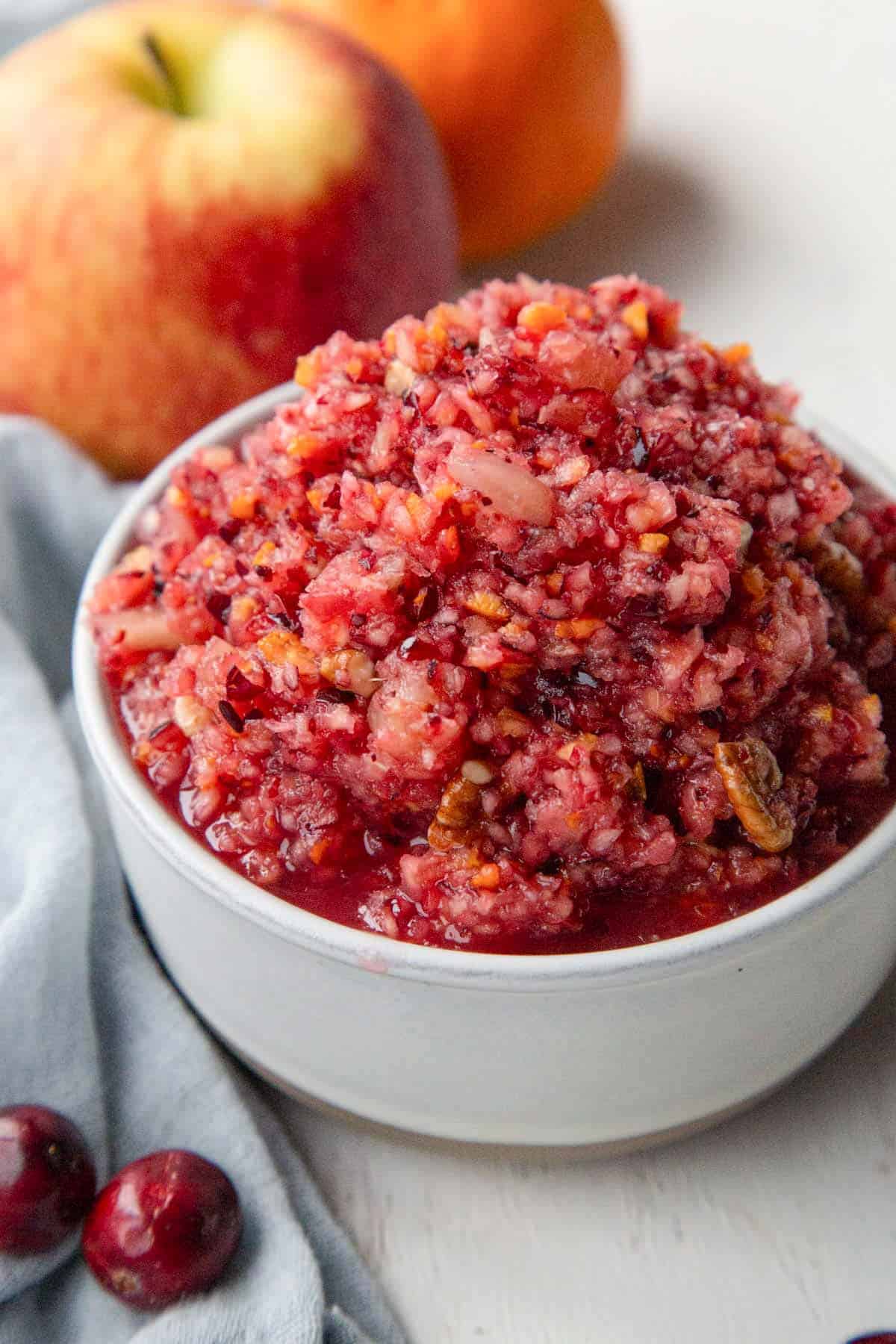 small dish filled with cranberry relish with finely chopped cranberries, bits of orange peel, pineapple, and pecans.