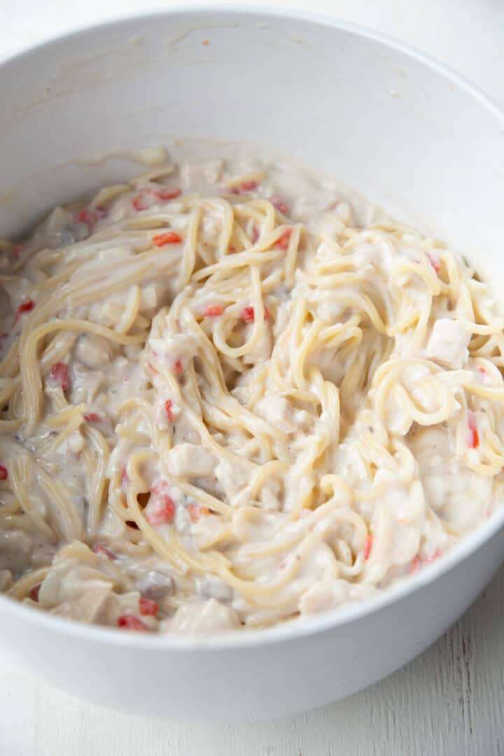 cooked spaghetti and pimentos in a creamy sauce in a bowl.