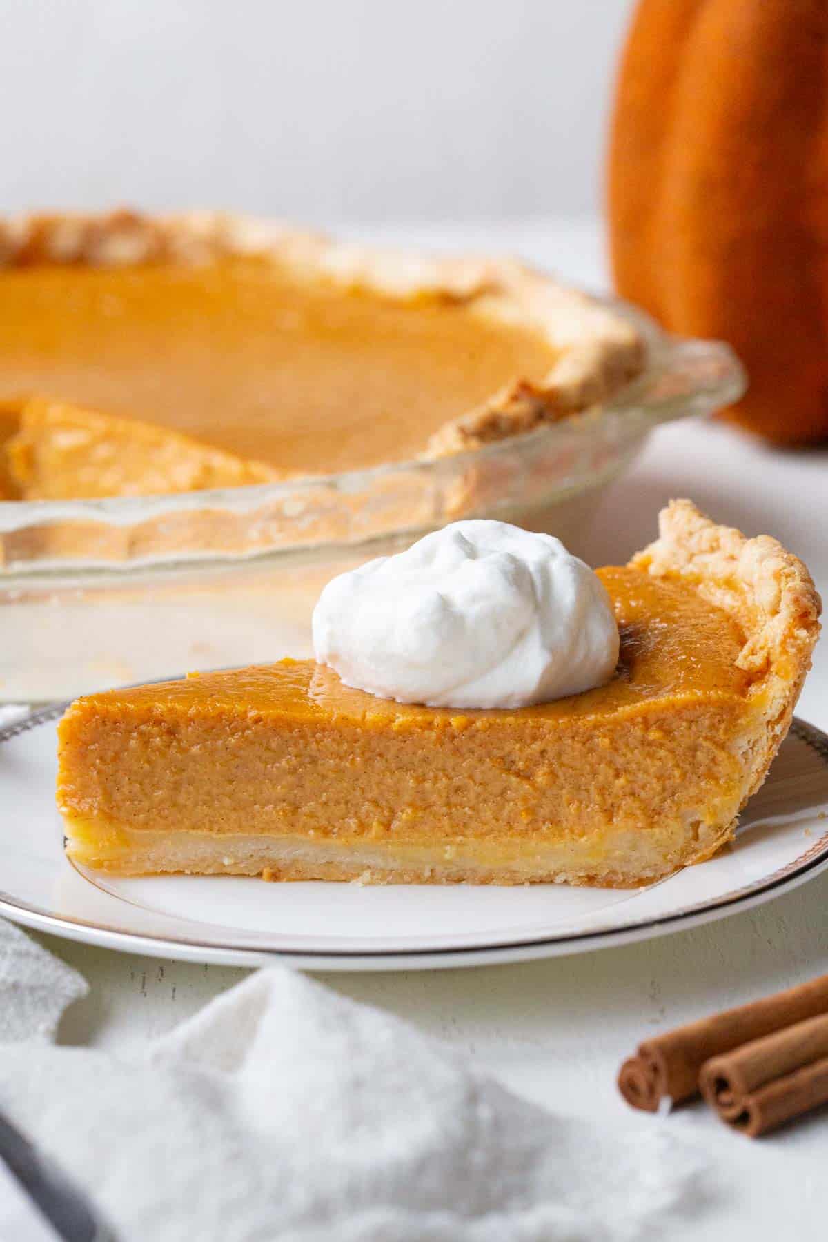 slice of pumpkin pie in a plate topped with a dollop of whipped cream.