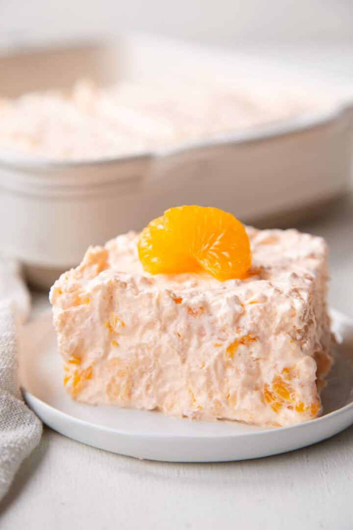 slice of orange gelatin salad with mandarin oranges inside and on top.