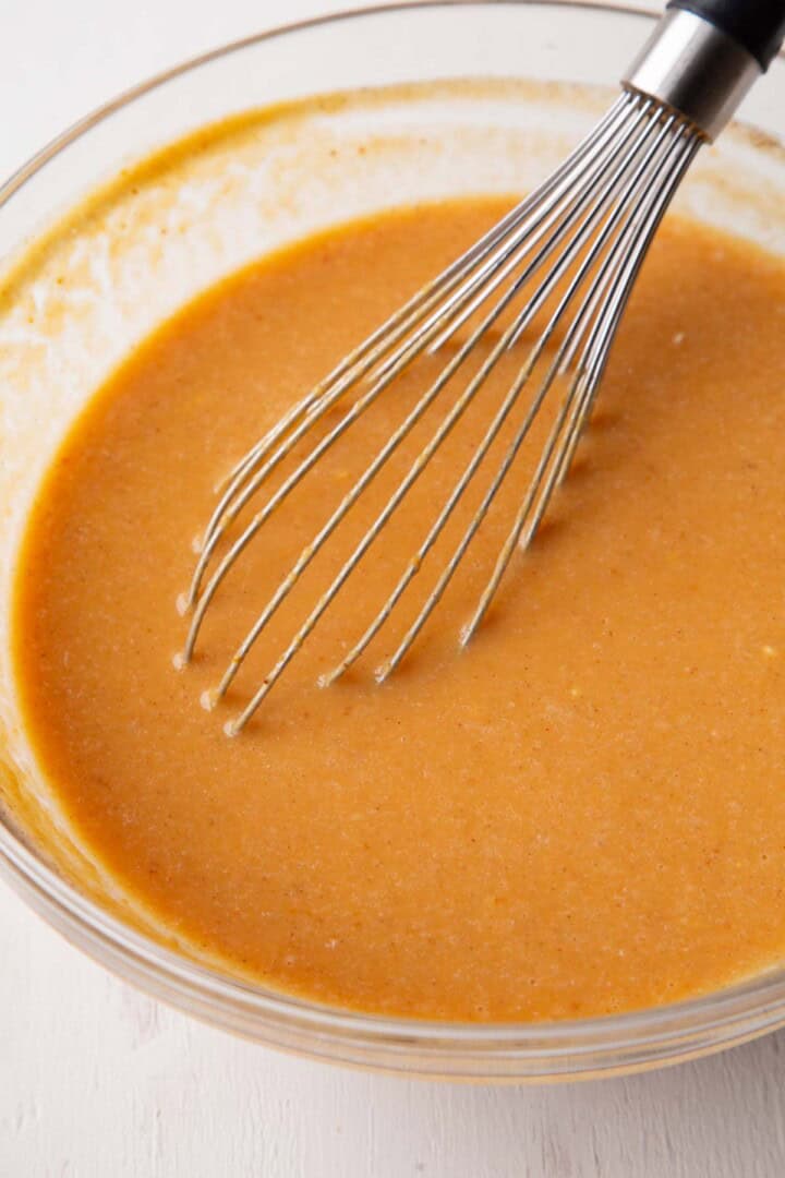 liquid pumpkin mixture in a bowl with a whisk.