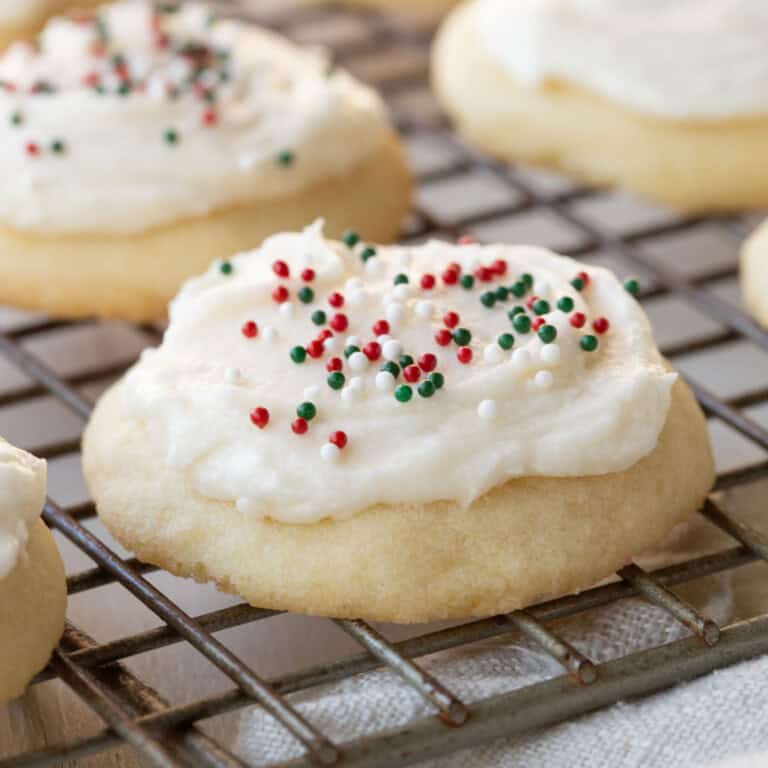 drop sugar cookie on a wire rack, topped with white frosting and red and green sprinkles.