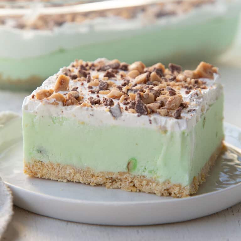 slice of a layered dessert with a ritz cracker crust, an ice cream pistachio pudding center, whipped topping and crushed Heath bars on top.