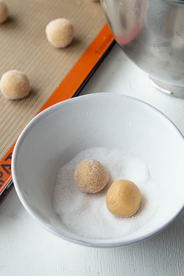 balls of peanut butter cookie dough being rolled in granulated sugar.