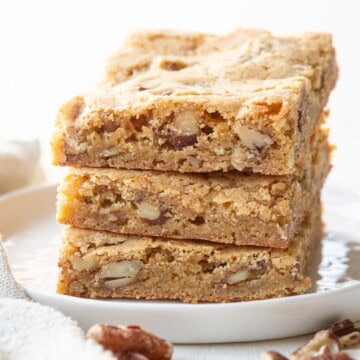 stack of three blondies with pecans inside on a white plate.