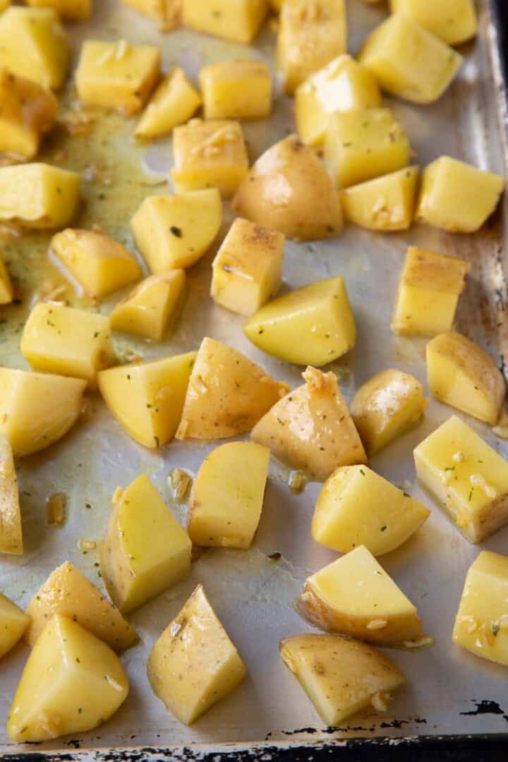 raw cubed potatoes on a metal baking sheet.