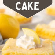 slice of lemon gooey butter cake with a yellow crust, yellow gooey layer, and whipped cream on top.