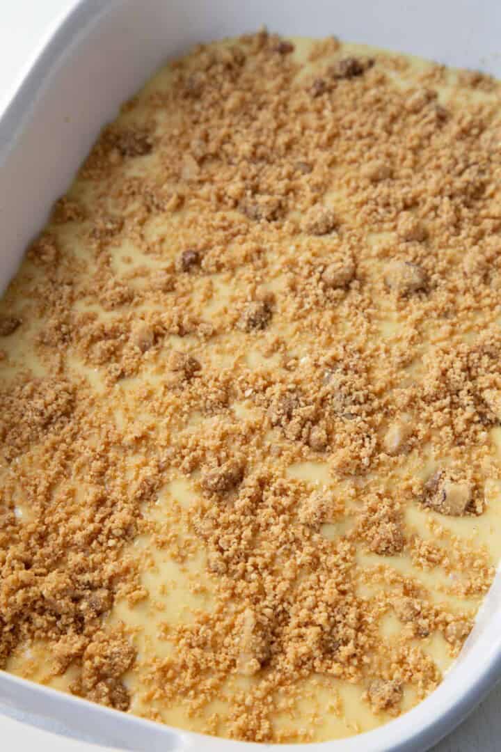 cake batter covered with graham cracker crumbs in a baking dish.