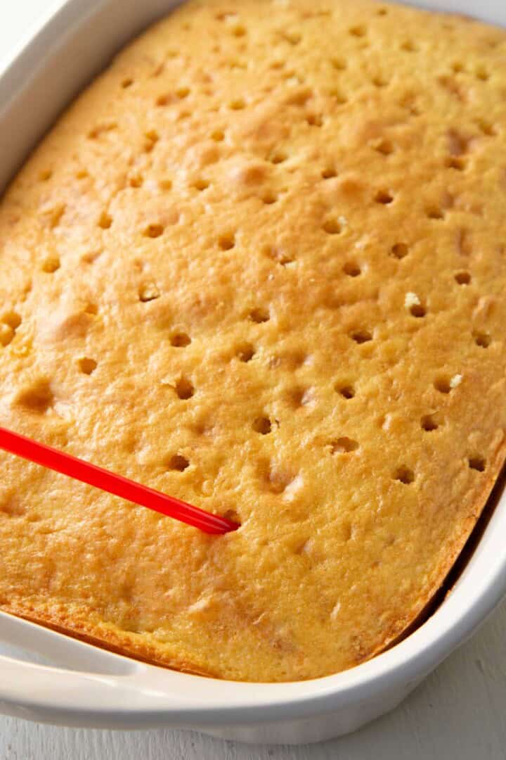 straw poking holes in a yellow cake.