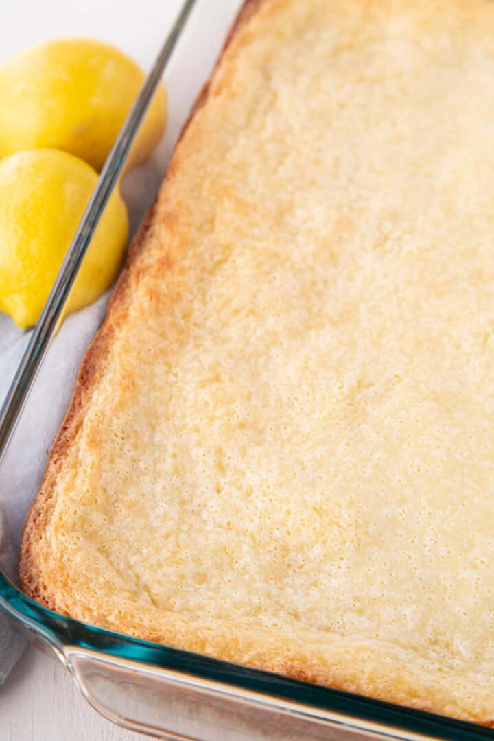 whole pan filled with a pale yellow cake, with lemons on the side.