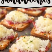 mini reuben sandwiches with a square of toasted rye bread topped with corned beef and melted swiss cheese on a sheet pan.