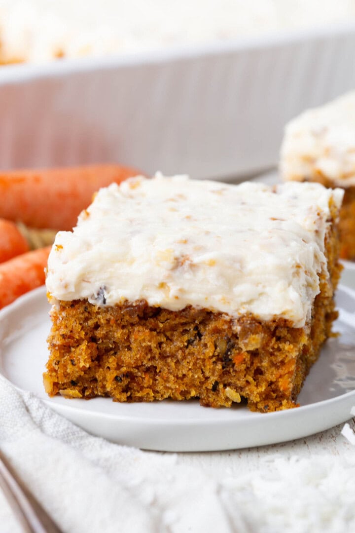 slice of carrot coconut cake with a thick layer of coconut cream cheese frosting.