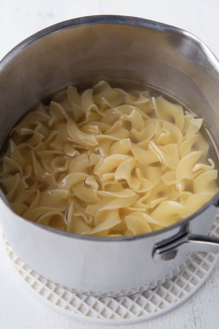 cooked egg noodles in water in a saucepan.