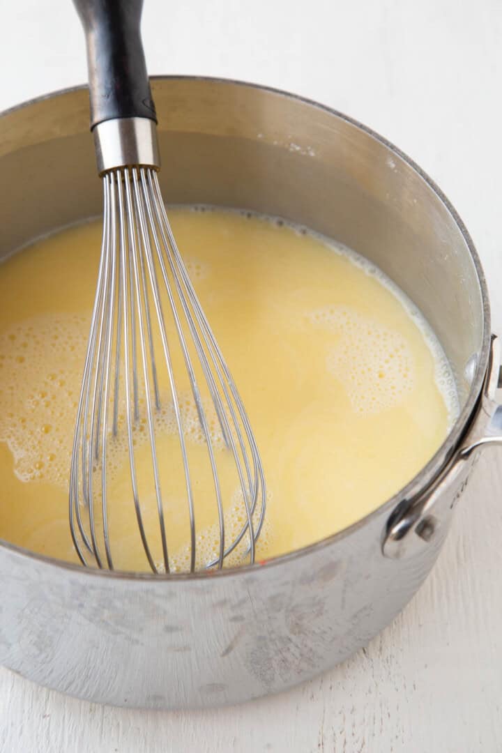 yellow lemon and egg liquid mixture in a saucepan with a whisk.