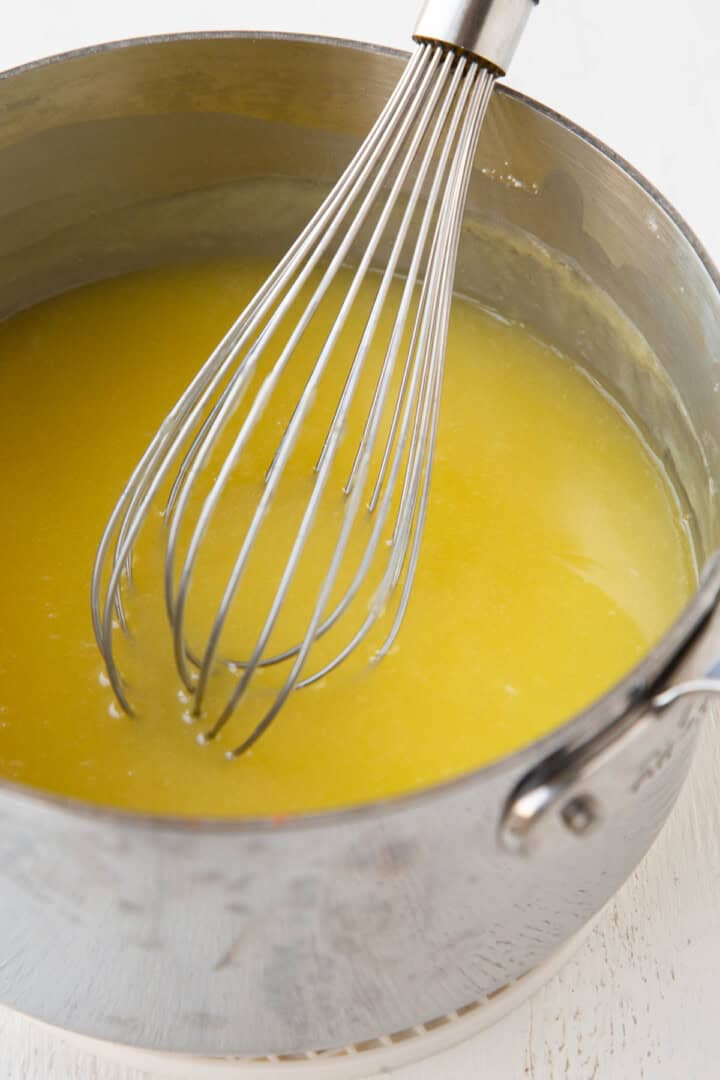 yellow firm liquid mixture in a saucepan with a whisk.