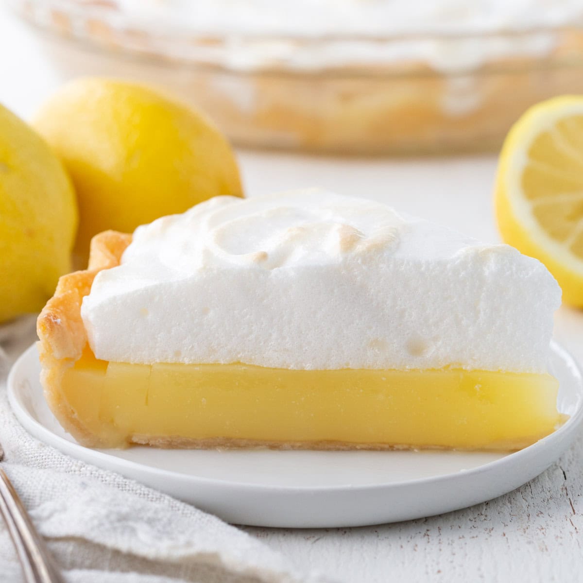 slice of lemon pie with a yellow lemon layer topped with fluffy meringue.