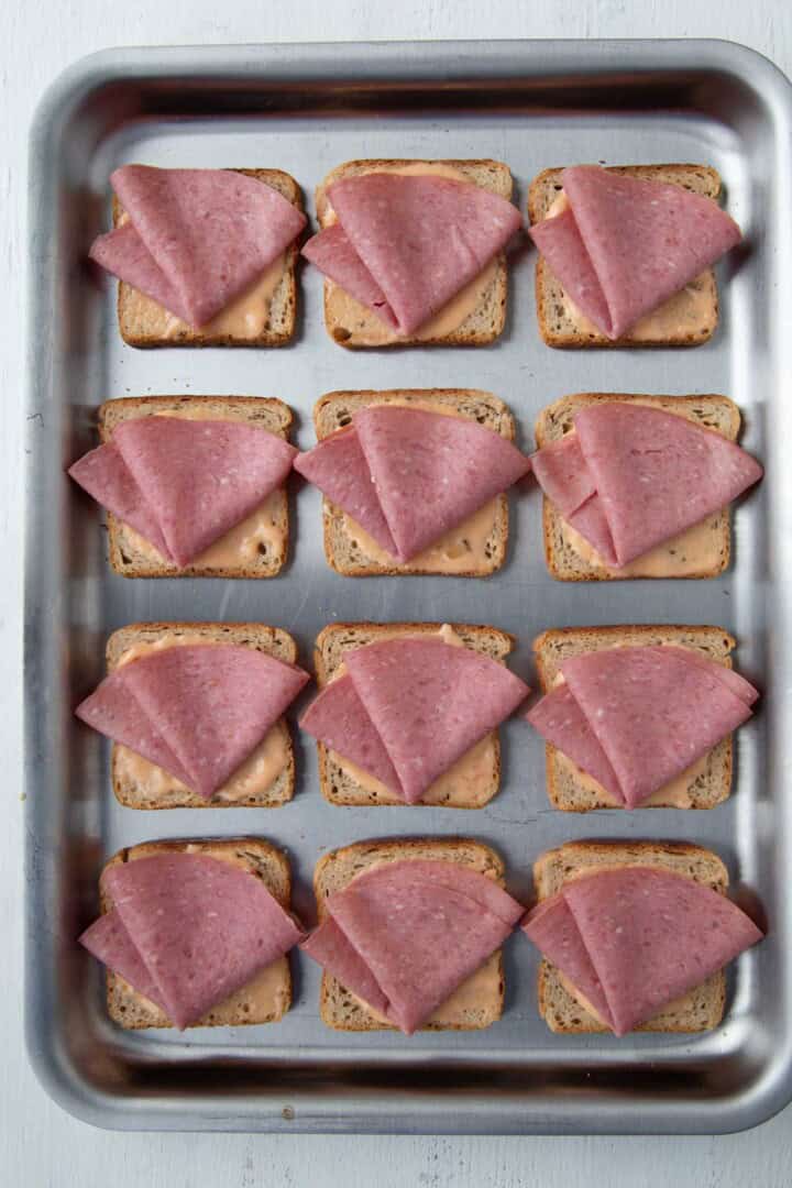 rye bread squares topped with thousand island dressing and sliced of corned beef.