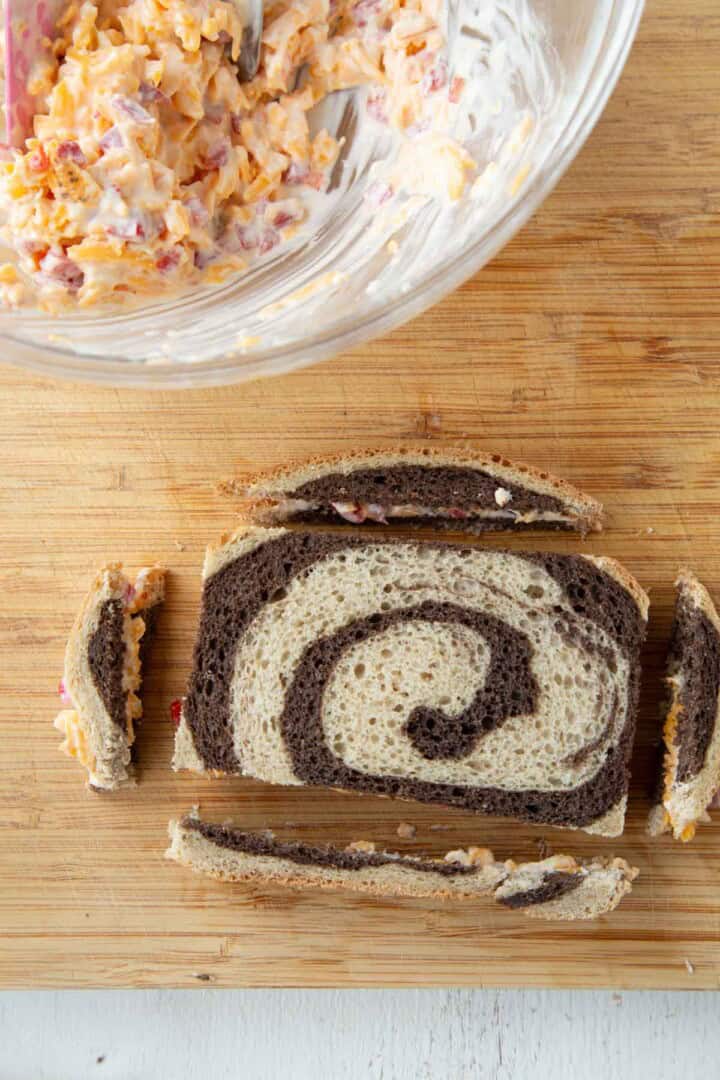 a slice of marble rye with pimento cheese inside and the crusts cut off the bread.