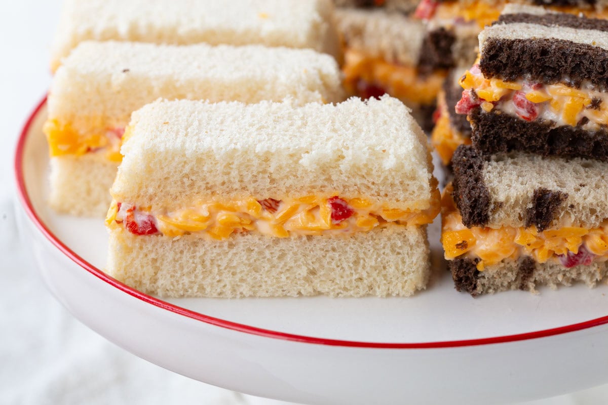 pimento cheese sandwiches on white bread and marble rye bread on a decorative platter.