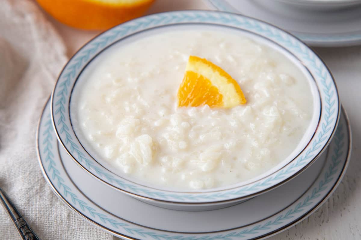 bowl full of creamy rice pudding with an orange slice garnish.