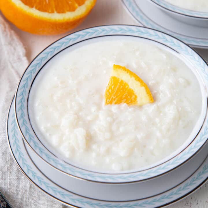 rice pudding in a decorative blue and white bowl, topped with a slice of orange.