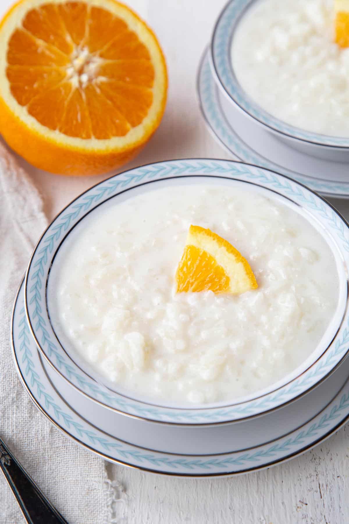 bowl of rice in a creamy white pudding, topped with a slice of orange.