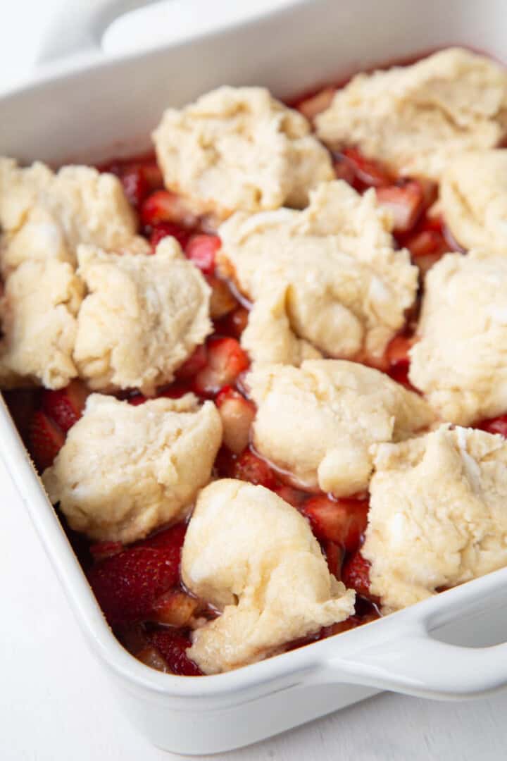 uncooked biscuit topping on top of cooked strawberries and rhubarb.