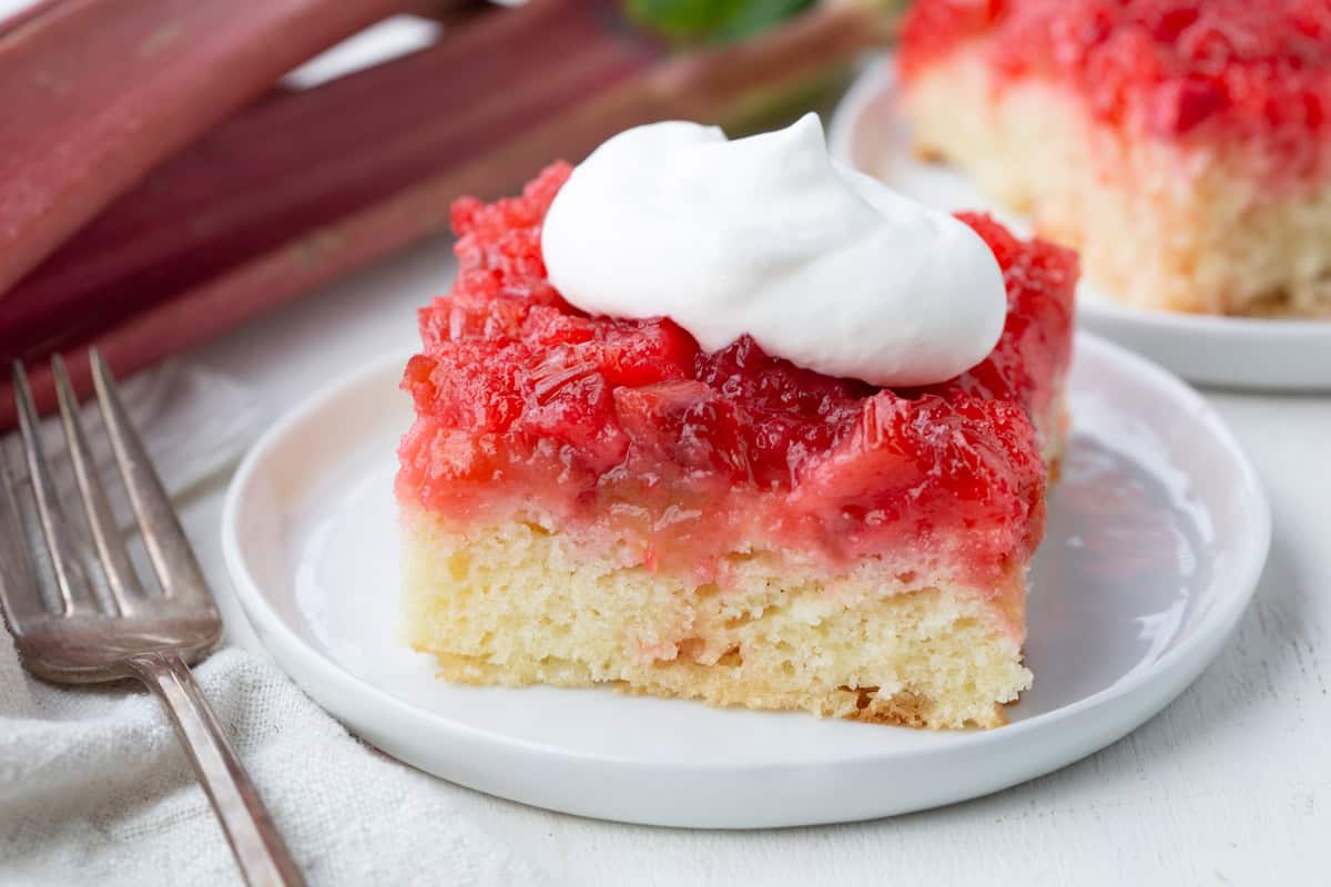 slice of rhubarb cake topped with a dollop of whipped cream.