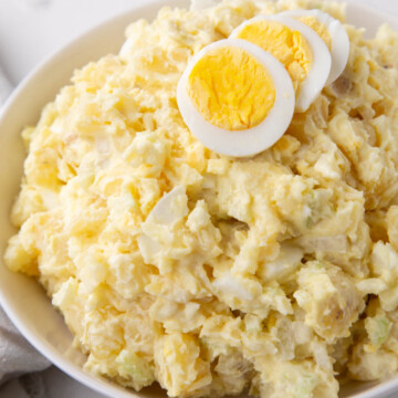 grandma's potato salad in a bowl topped with slices of hard boiled eggs.
