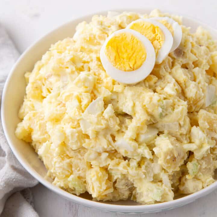 grandma's potato salad in a bowl topped with slices of hard boiled eggs.