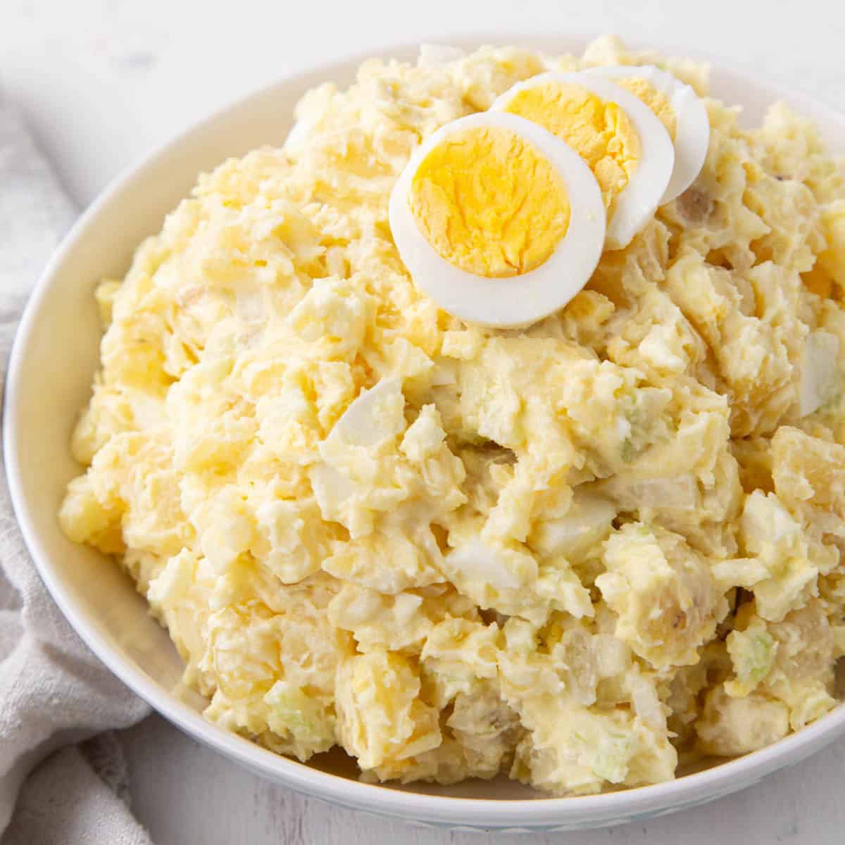 grandma's potato salad in a bowl topped with slices of hard boiled eggs.