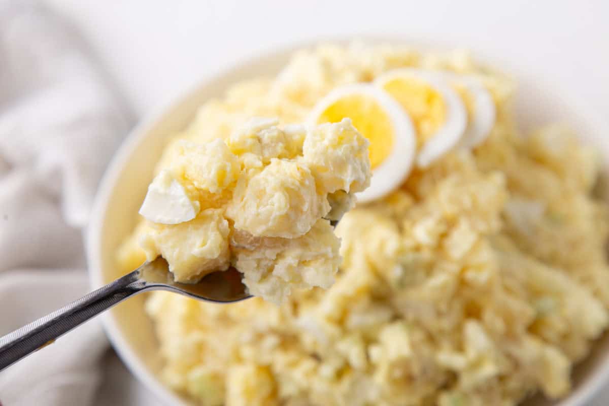 spoon holding up a scoop of creamy potato salad.