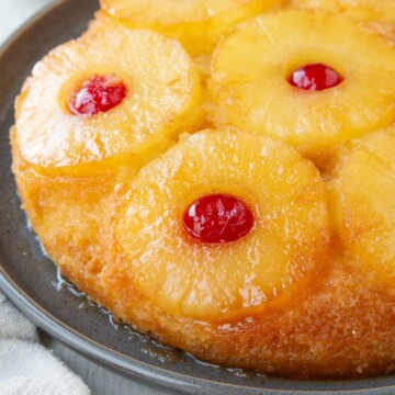round yellow pineapple upside down cake topped with pineapple rings and maraschino cherries.
