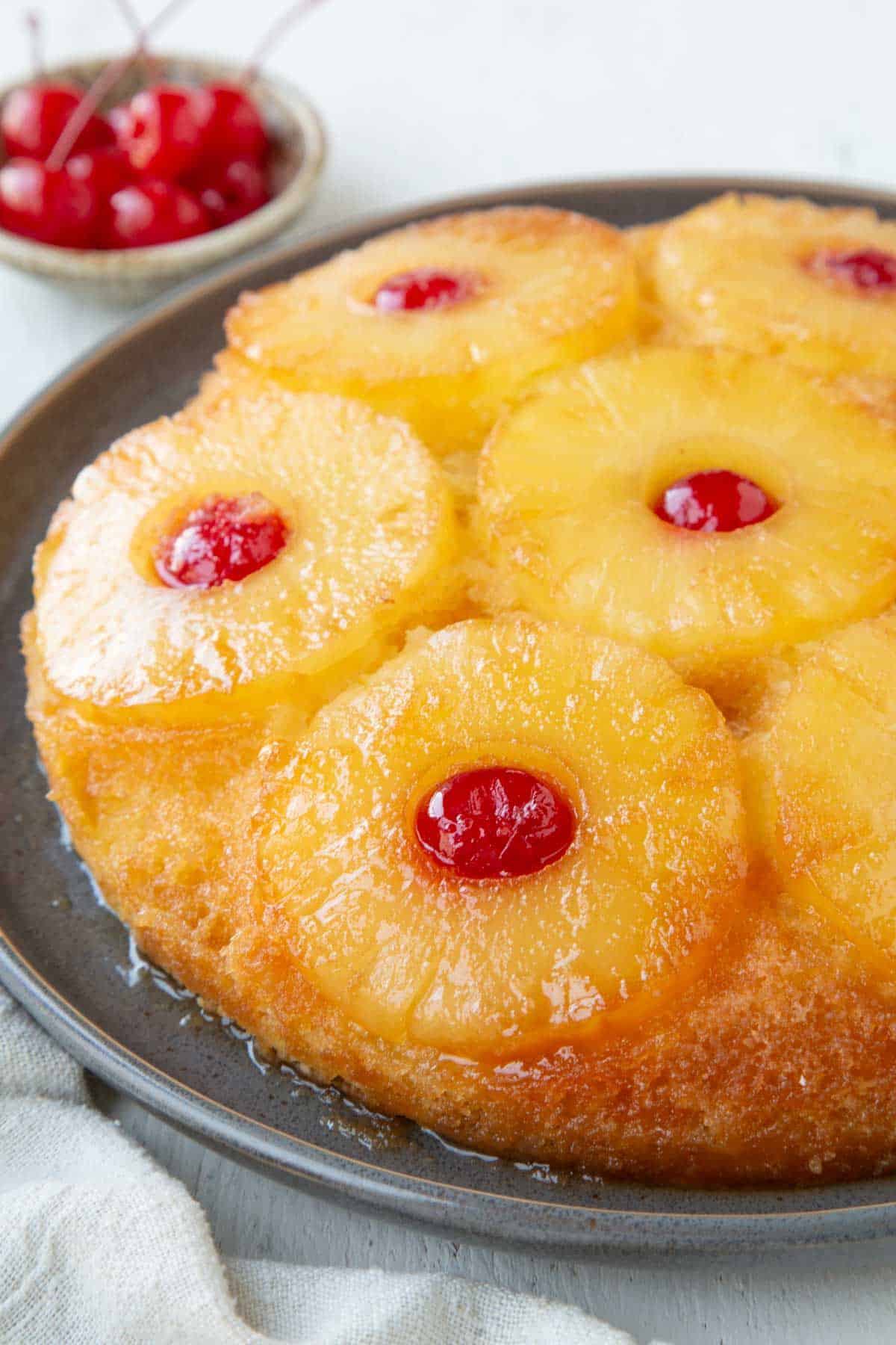 whole round pineapple upside down cake topped with pineapple rings and maraschino cherries.