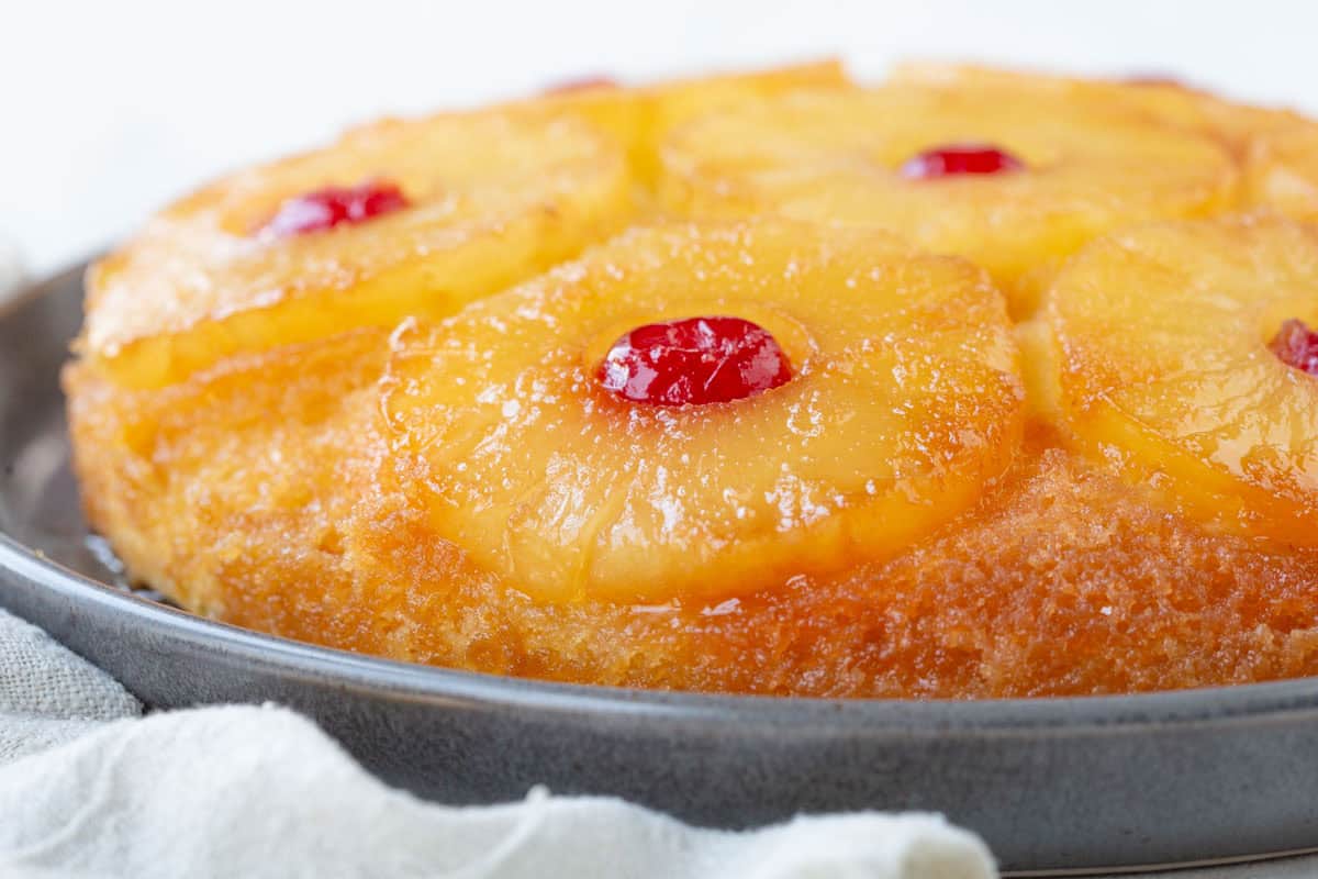 whole round pineapple upside down cake with pineapple rings and cherries.