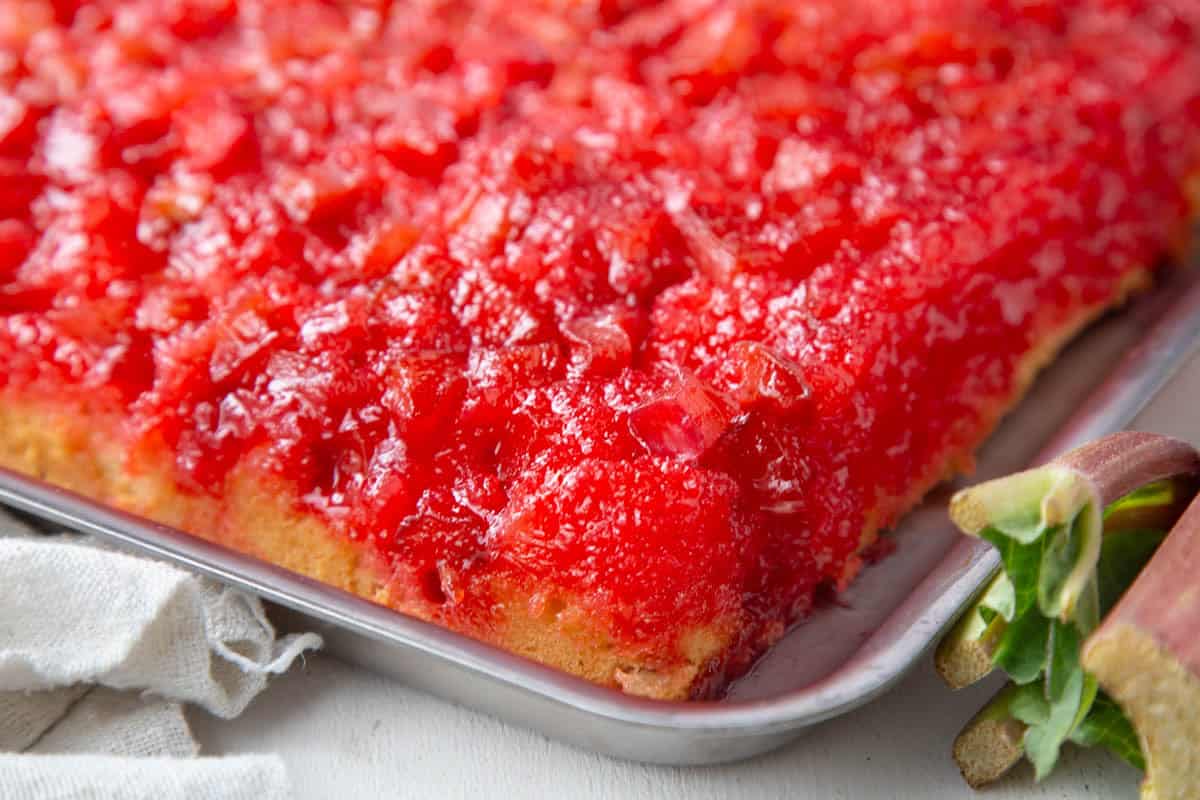 whole rhubarb upside down cake with yellow cake on the bottom and a bright pink rhubarb mixture on top.