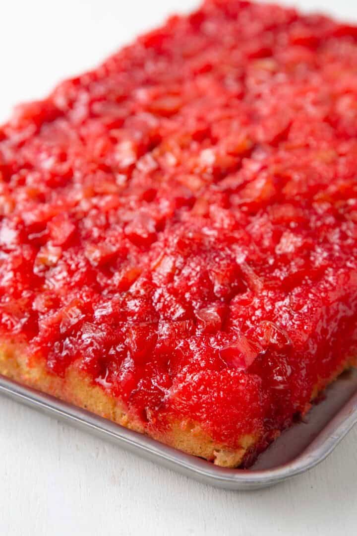 rhubarb upside down cake with yellow cake on the bottom and a bright red rhubarb mixture on top.