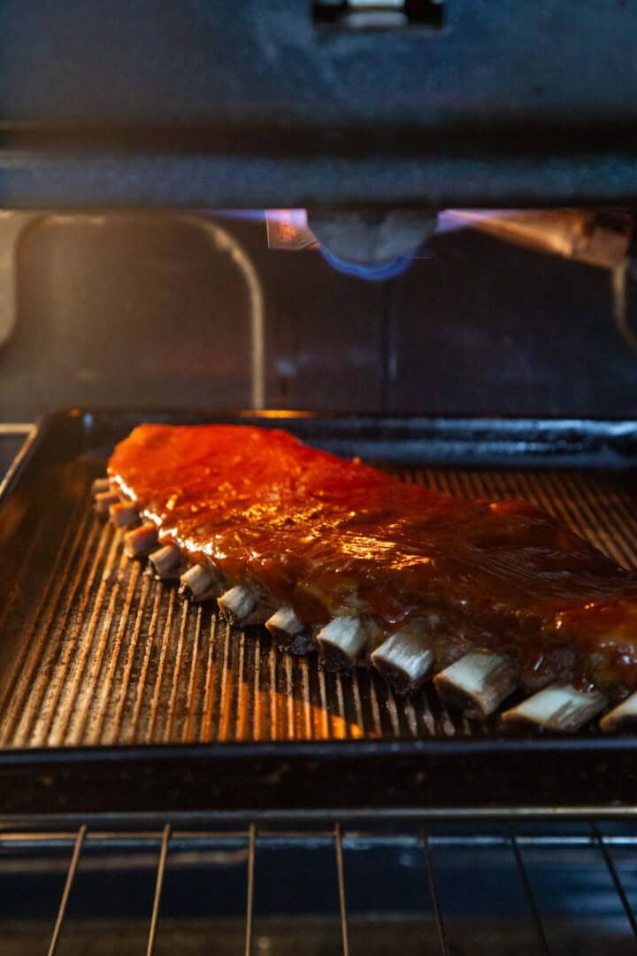 ribs covered with bbq sauce under the broiler in the oven.