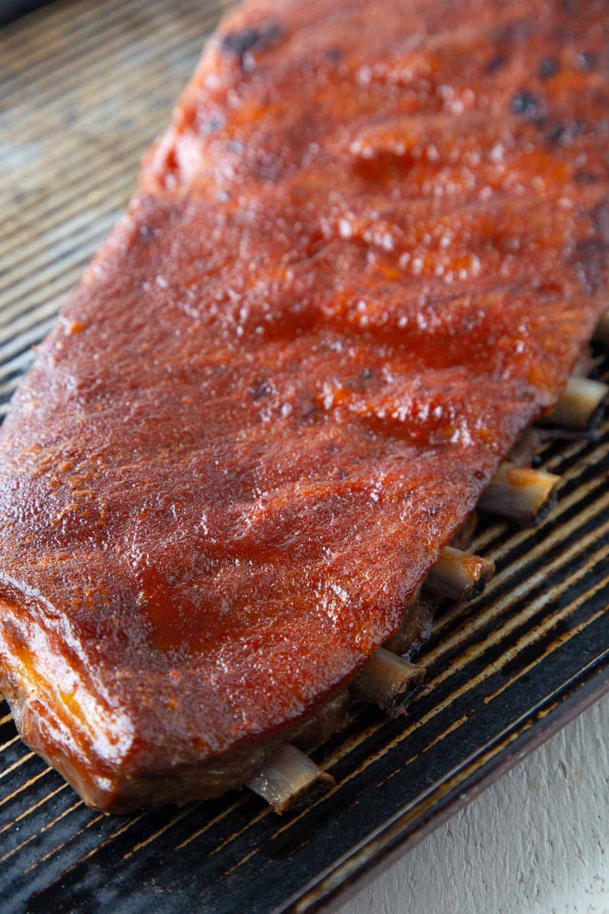 rack of st. louis style ribs with a thin layer of bbq sauce, sitting on a baking sheet.