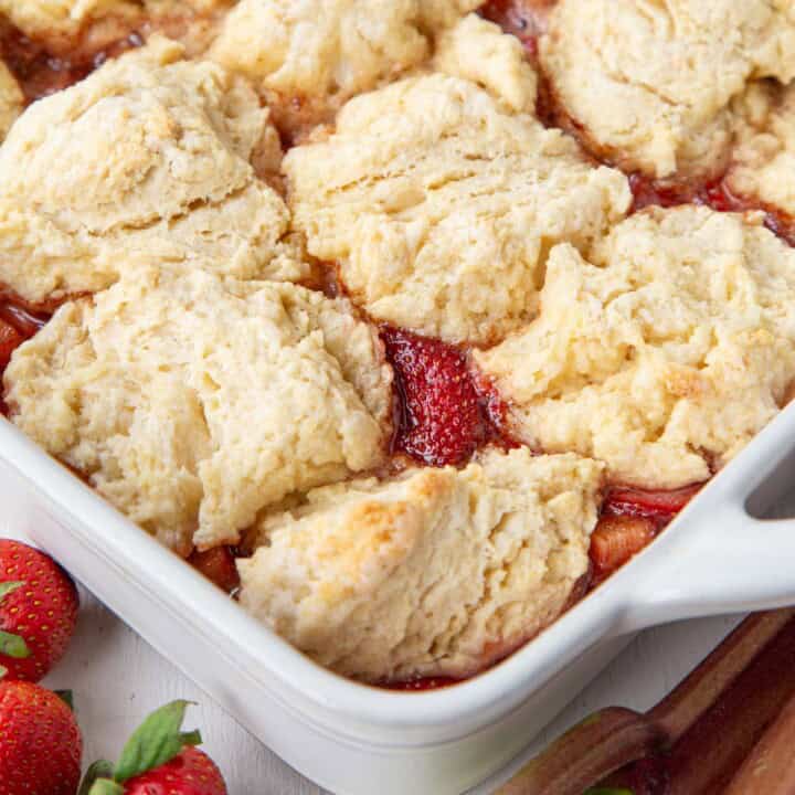 strawberry rhubarb cobbler topped with biscuits in a baking dish.