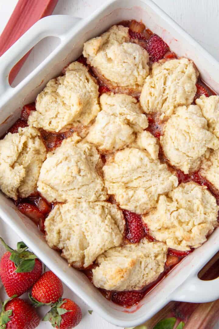 dish filled with baked strawberry rhubarb cobbler with a biscuit-like topping.