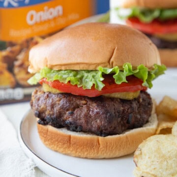 burger with french onion soup mix inside, topped with tomato and lettuce on a brioche bun.
